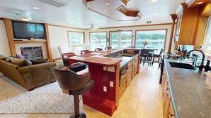A spacious kitchen with a large island, a fireplace, and a view of a lake.