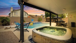 A backyard with a hot tub, a swimming pool, and a hammock. - Spacious 4 BR -SaltwaterHotTub -Pool -Sleeps 11 (Peoria)