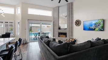 Ein modernes Wohnzimmer mit einem Ecksofa, einem Kamin und einem Fernseher an der Wand.