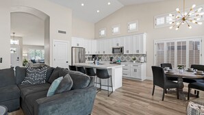 A spacious kitchen with white cabinets, a central island, and a dining area with a table and chairs. - Spacious 4 BR -SaltwaterHotTub -Pool -Sleeps 11 (Peoria)