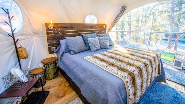 Alojamiento en una tienda de campaña acogedora, con cama y cabecero de madera, y vistas al exterior.