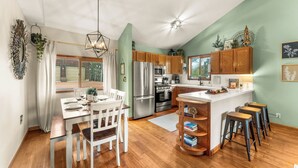 A modern kitchen with wooden cabinets, stainless steel appliances, and a central island with stools.