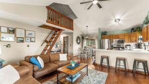 A spacious living room with a brown leather sofa, wooden coffee table, and a staircase leading to an upper level.