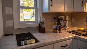 A kitchen with white cabinets, a window, a stove, and various kitchen items on the counter.