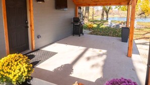 A covered outdoor area with a ceiling fan, a grill, and a view of a lake.