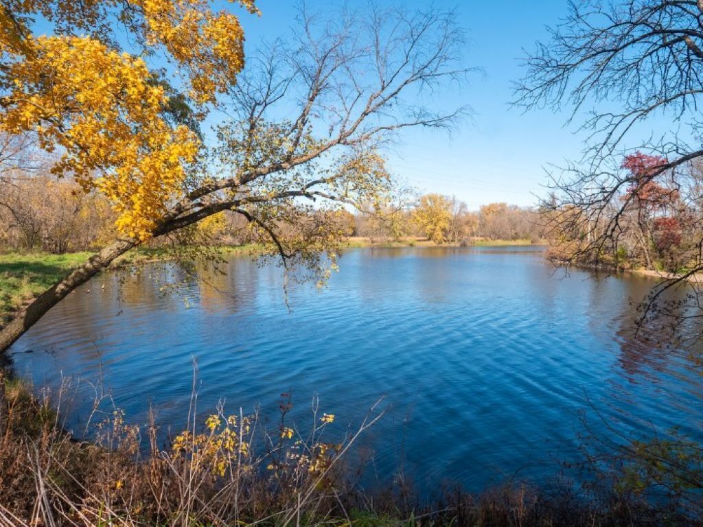 A calm lake surrounded by trees with autumn foliage.