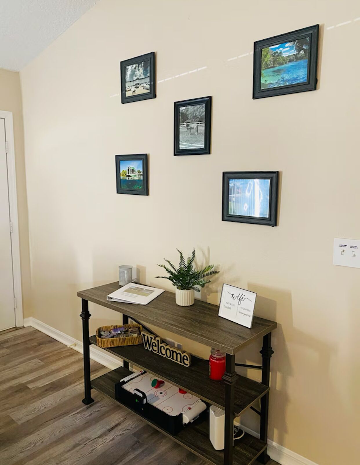 Un comptoir d’accueil avec une pancarte « Bienvenue », des tableaux encadrés accrochés au mur et une plante en pot.