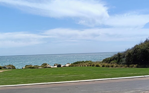 A coastal road with a grassy area and a view of the sea.