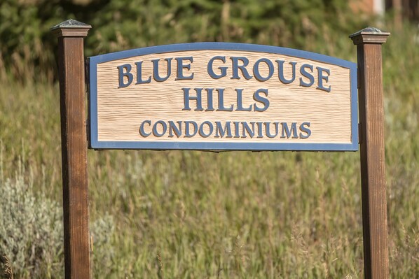 Un panneau en bois portant l’inscription « BLUE GROUSE HILLS CONDOMINIUMS ».