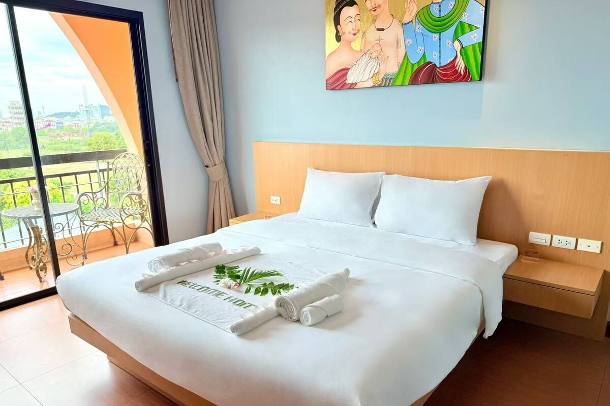 Una habitación de hotel con una cama grande, un balcón con vistas y un cuadro en la pared.
