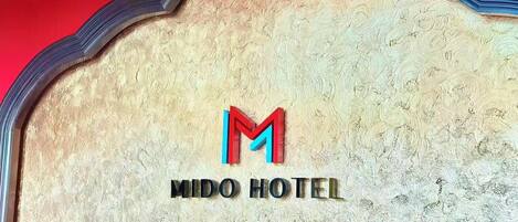 A textured wall with a logo and the name "MIDO HOTEL" in capital letters.