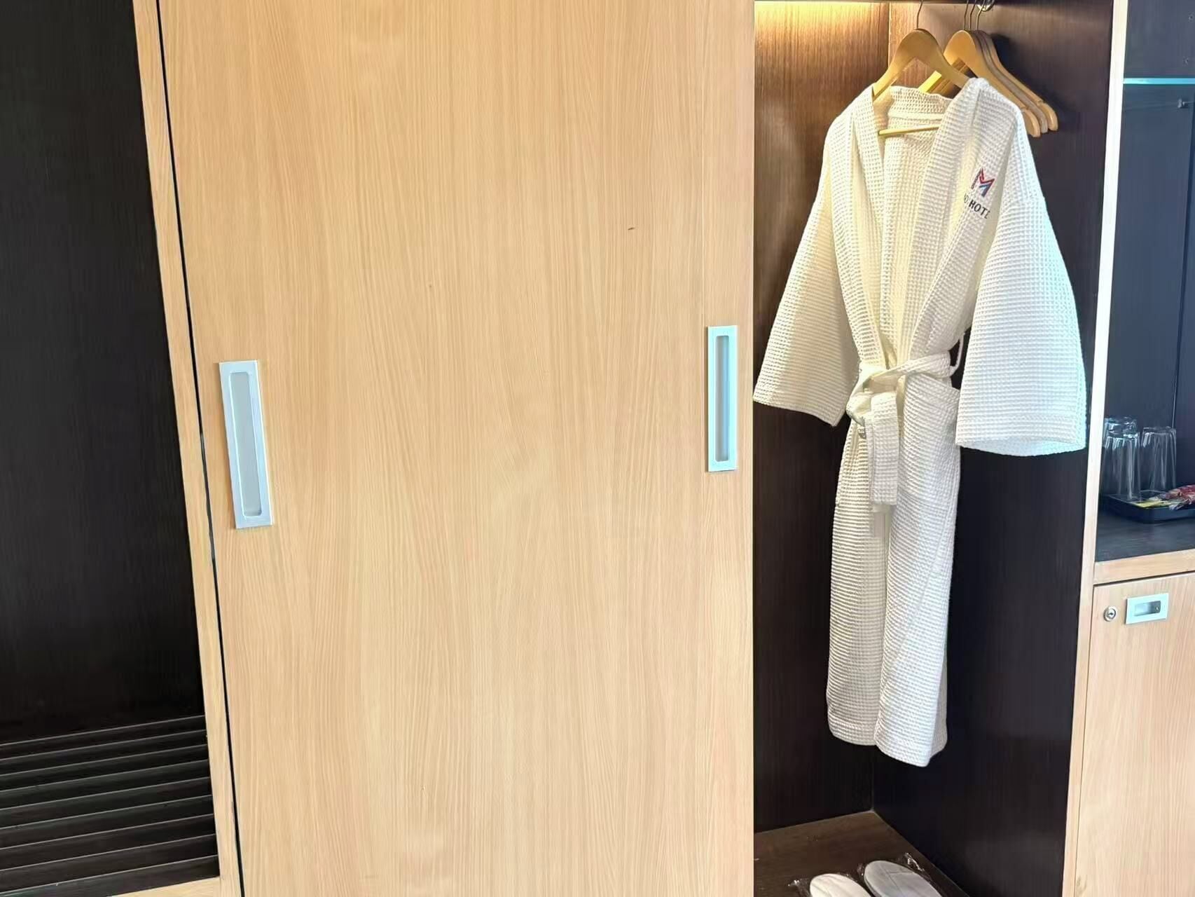 A wooden wardrobe with a robe hanging on a rack.