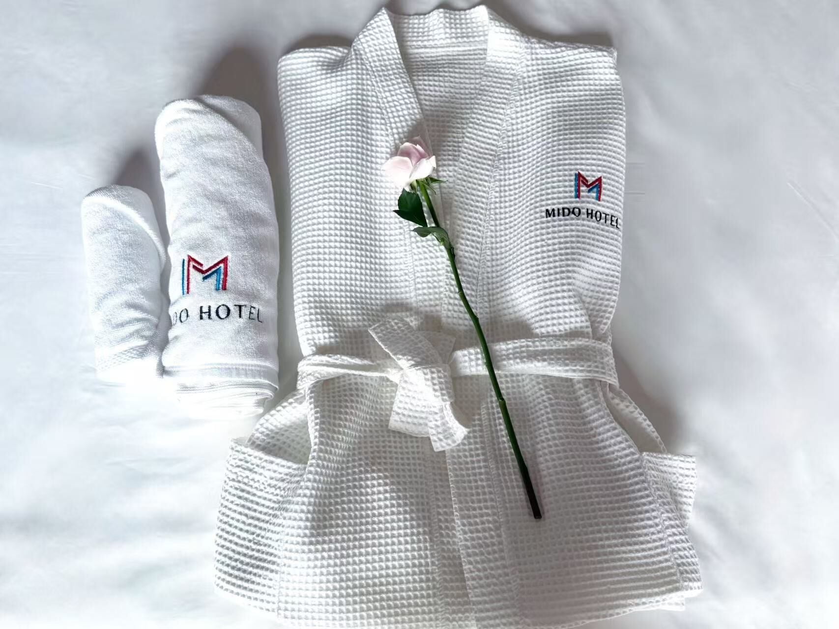 A white robe with a logo and text indicating it is from MIDO HOTEL.
