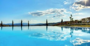 Piscina azul cristalina con vistas a montañas y árboles distantes.