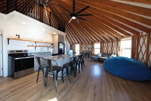 A spacious kitchen with a high ceiling, wooden beams, and a large island with bar stools.