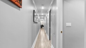A long, narrow hallway with light-colored walls and wooden flooring. - DC Urban Retreat+3Bed+Newly Renovated (Washington)