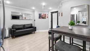 A modern living room with a black leather sofa, a wooden dining table, and a large mirror. - DC Urban Retreat+3Bed+Newly Renovated (Washington)