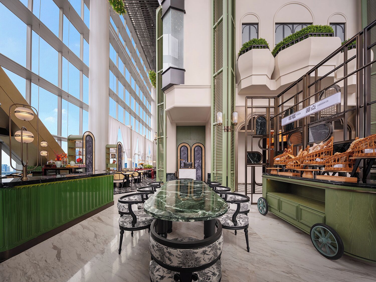 Un hall d’hôtel spacieux avec une table en verre au centre, entourée de chaises, un comptoir de réception vert et une exposition de meubles en osier.