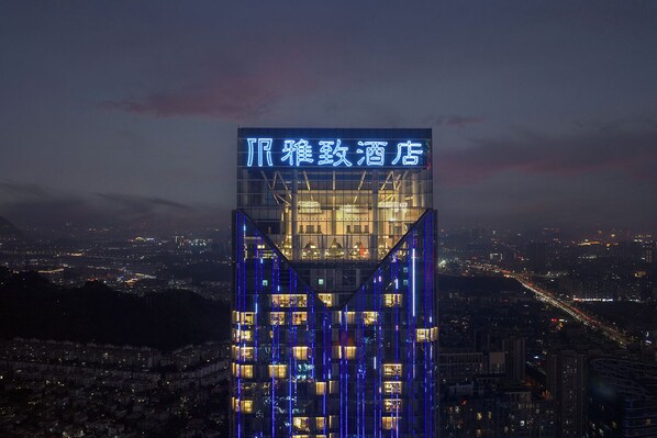 A high-rise building with illuminated signage and vertical light accents. - Guangzhou Panyu Wanbo Elegant Hotel - Free Shuttle Bus During the Canton Fair (Guangzhou)