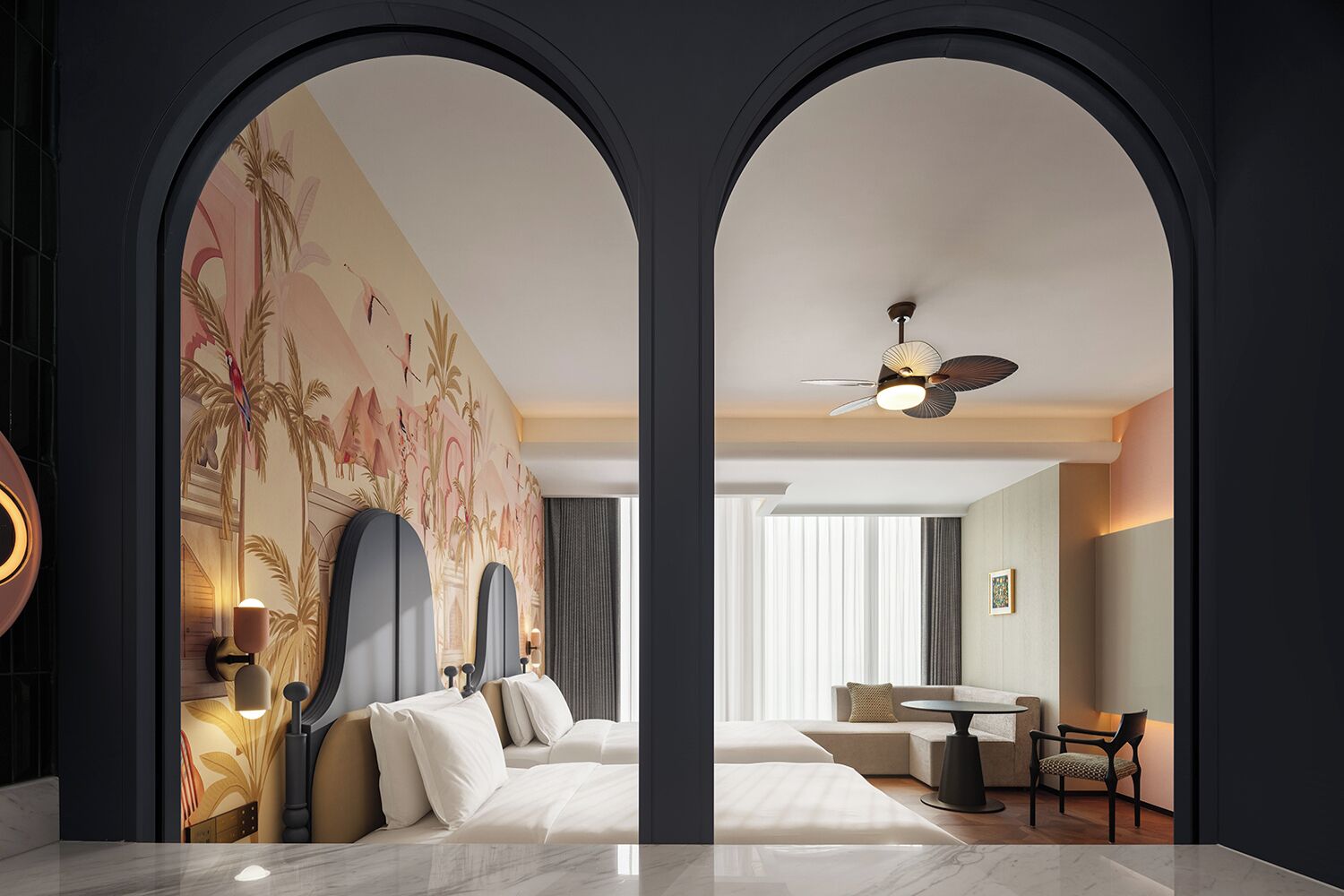 Ein Hotelzimmer mit Bett, Schreibtisch, Sessel, Deckenventilator und großem Fenster.
