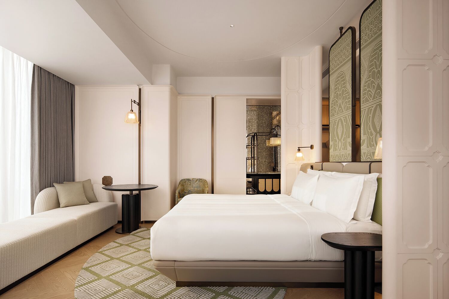 A hotel room with a bed, a seating area, a small table, and a mirror.