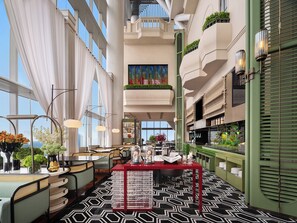 A spacious atrium with high ceilings, large windows, and a central dining area with a red table.