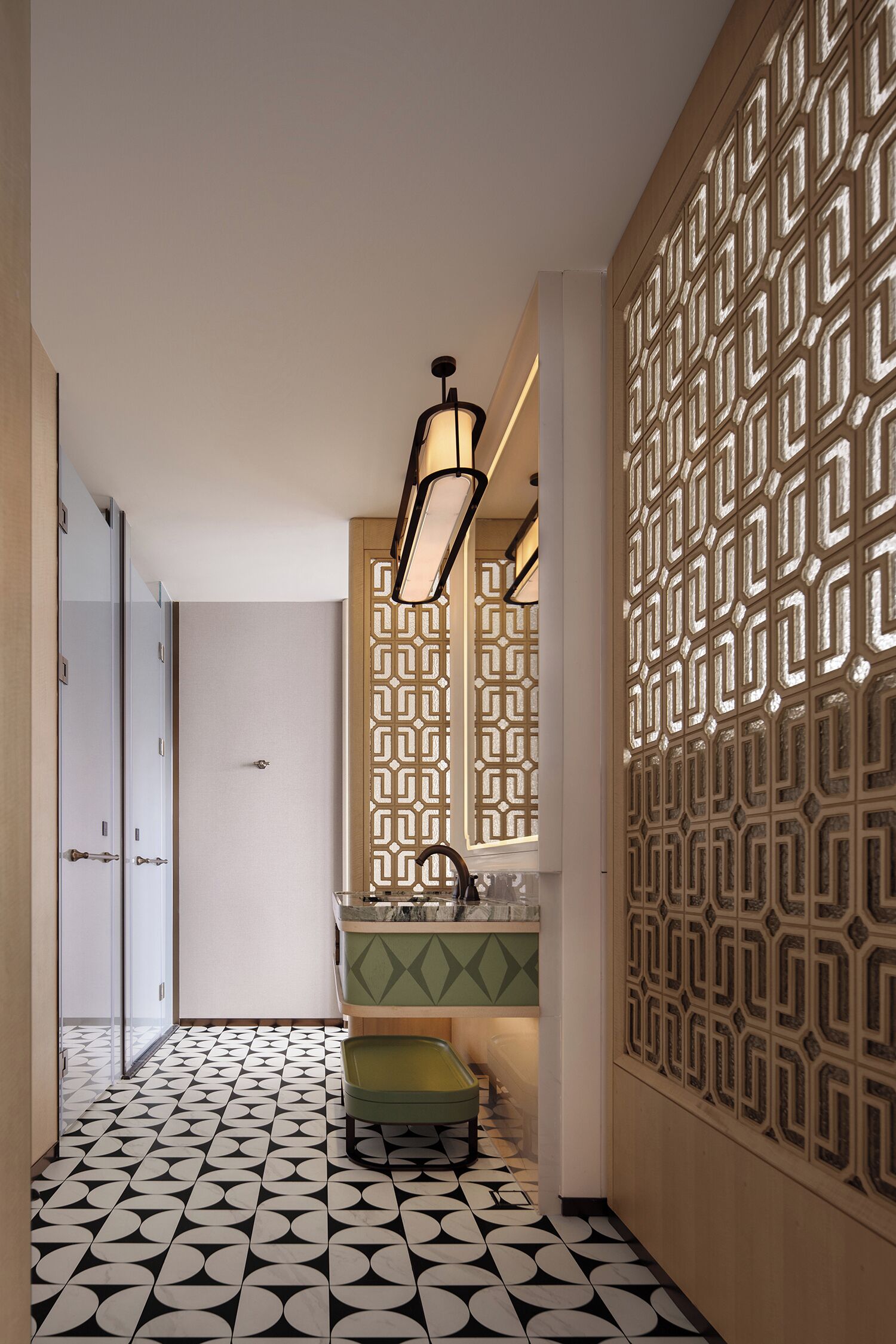 A hallway with patterned flooring, a green bench, a sink, and a decorative wall panel.