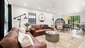 Ein modernes Wohnzimmer mit Ledersofas, einem runden Couchtisch und einem Essbereich mit Stühlen und Tisch.