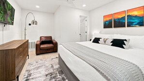 Ein Schlafzimmer mit einem Bett, einem Sessel, einem Schreibtisch und Bildern an der Wand.