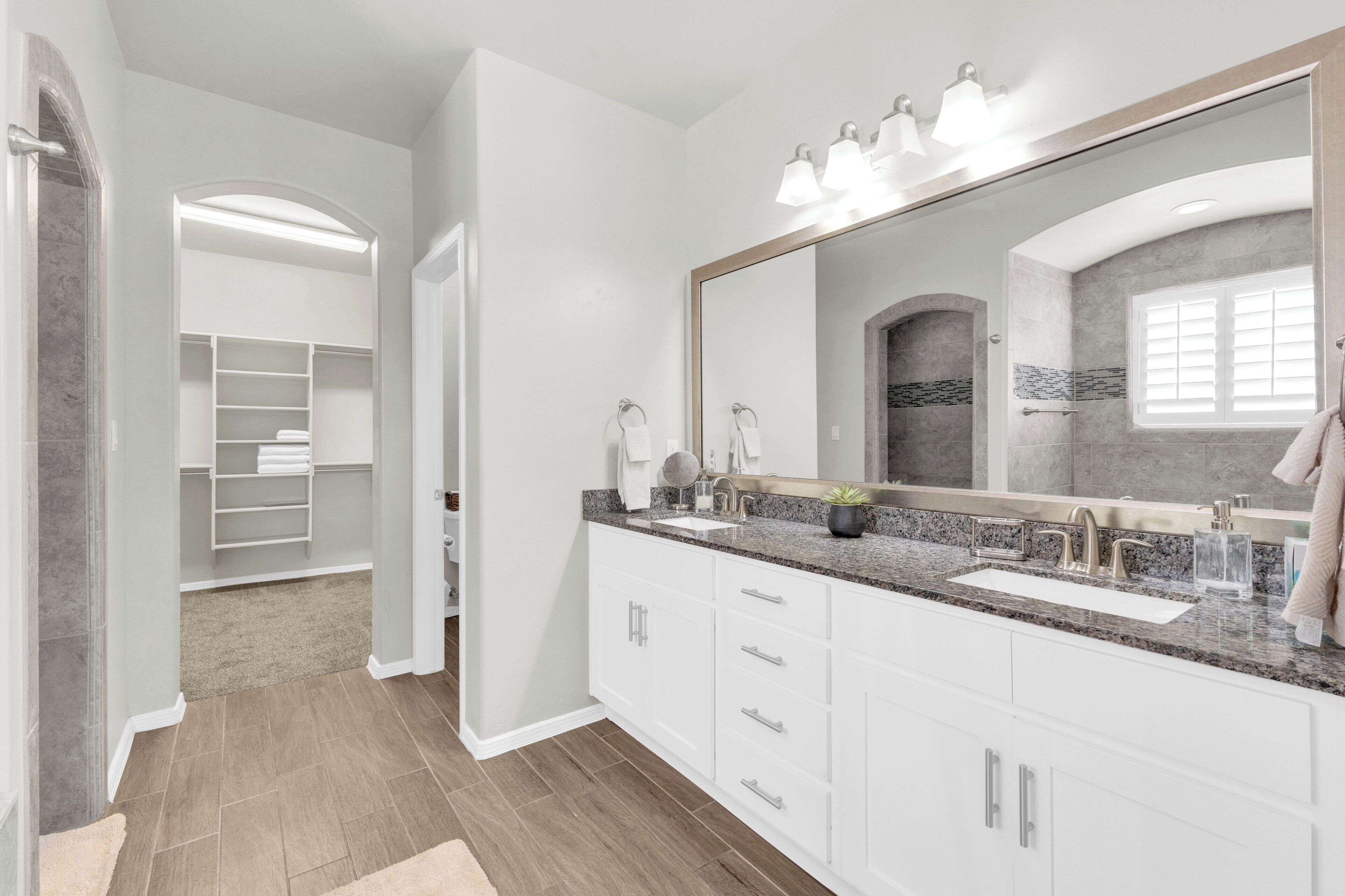 A modern bathroom with a large vanity, a walk-in shower, and a built-in shelving unit.