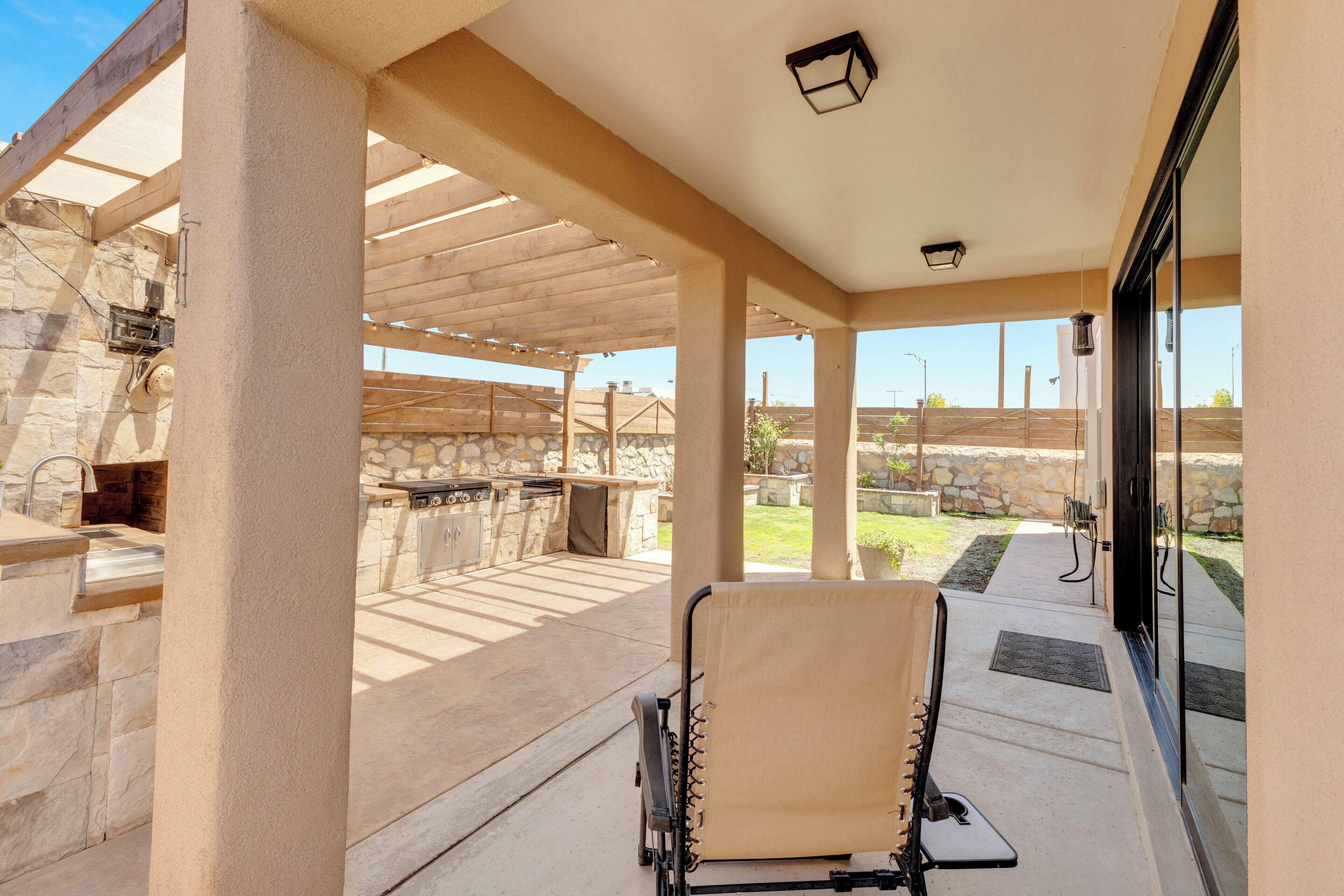 An outdoor patio with a stone fireplace, a grill, and a covered seating area.