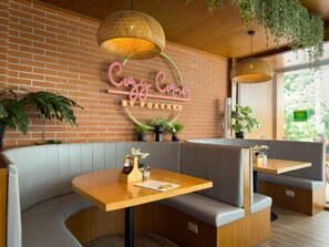 A cozy cafe with a neon sign, wooden tables, grey cushioned seating, and hanging plants. - Boutique Bliss 1BR T1-506 (Chalong)