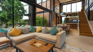 Een moderne woonkamer met een modulaire bank, een salontafel en uitzicht op een zwembad en tuin.