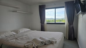 Ein Hotelzimmer mit Bett, einem Vorhangfenster und Blick auf Grün.