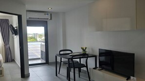 Een moderne woonkamer met een flatscreen televisie, een eettafel met stoelen en uitzicht op zonnepanelen.