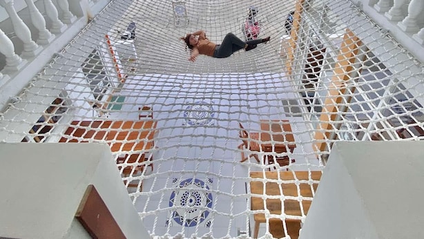 Une personne allongée sur une terrasse en filet, avec vue sur l’océan.