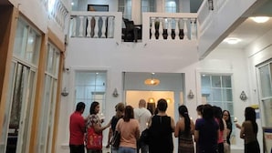 Un hall d'hôtel avec une enseigne verte sur laquelle on peut lire « Ola de Baler », et un groupe de personnes se tenant au centre.