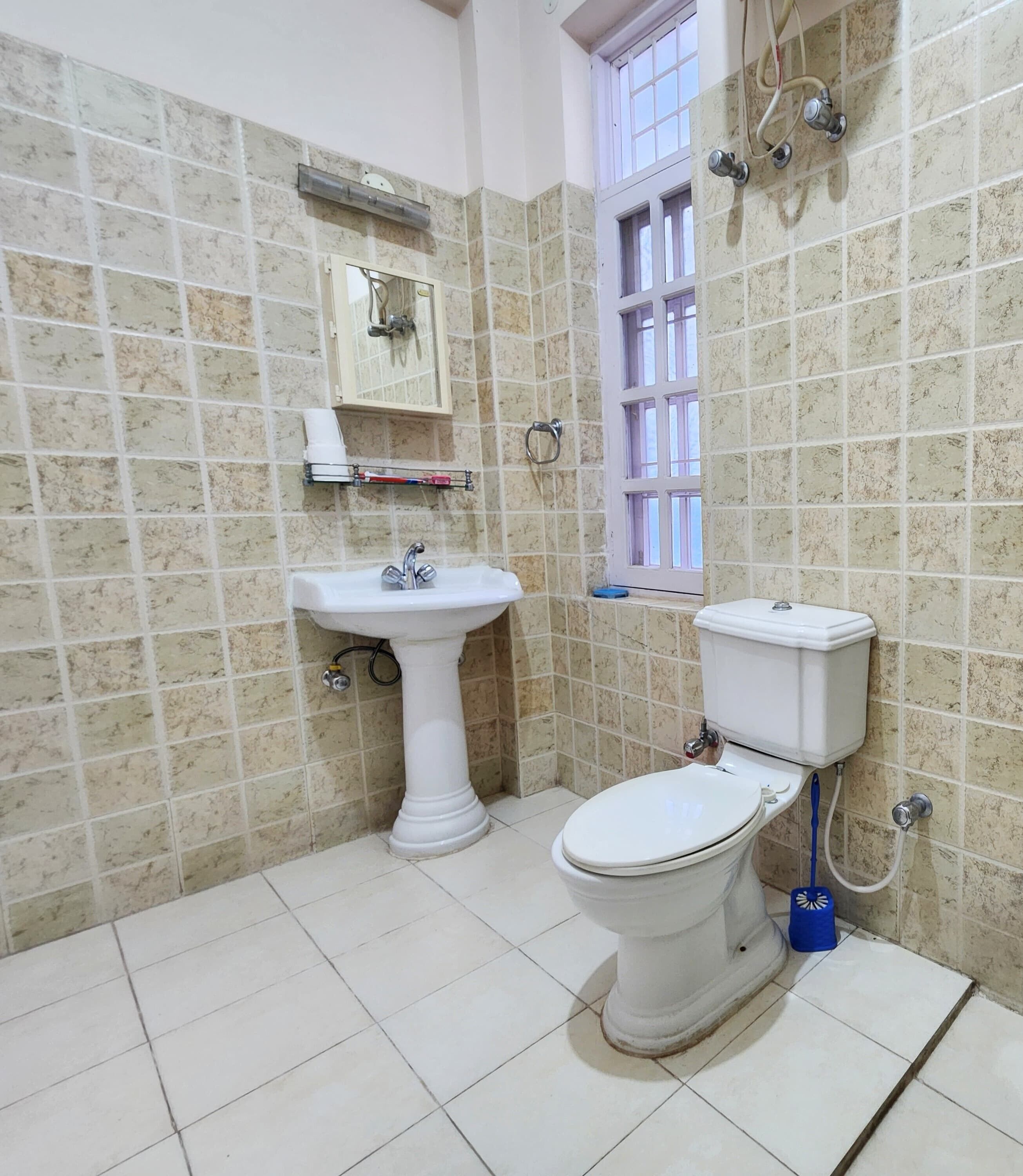 A bathroom with a pedestal sink, toilet, and a window with bars.