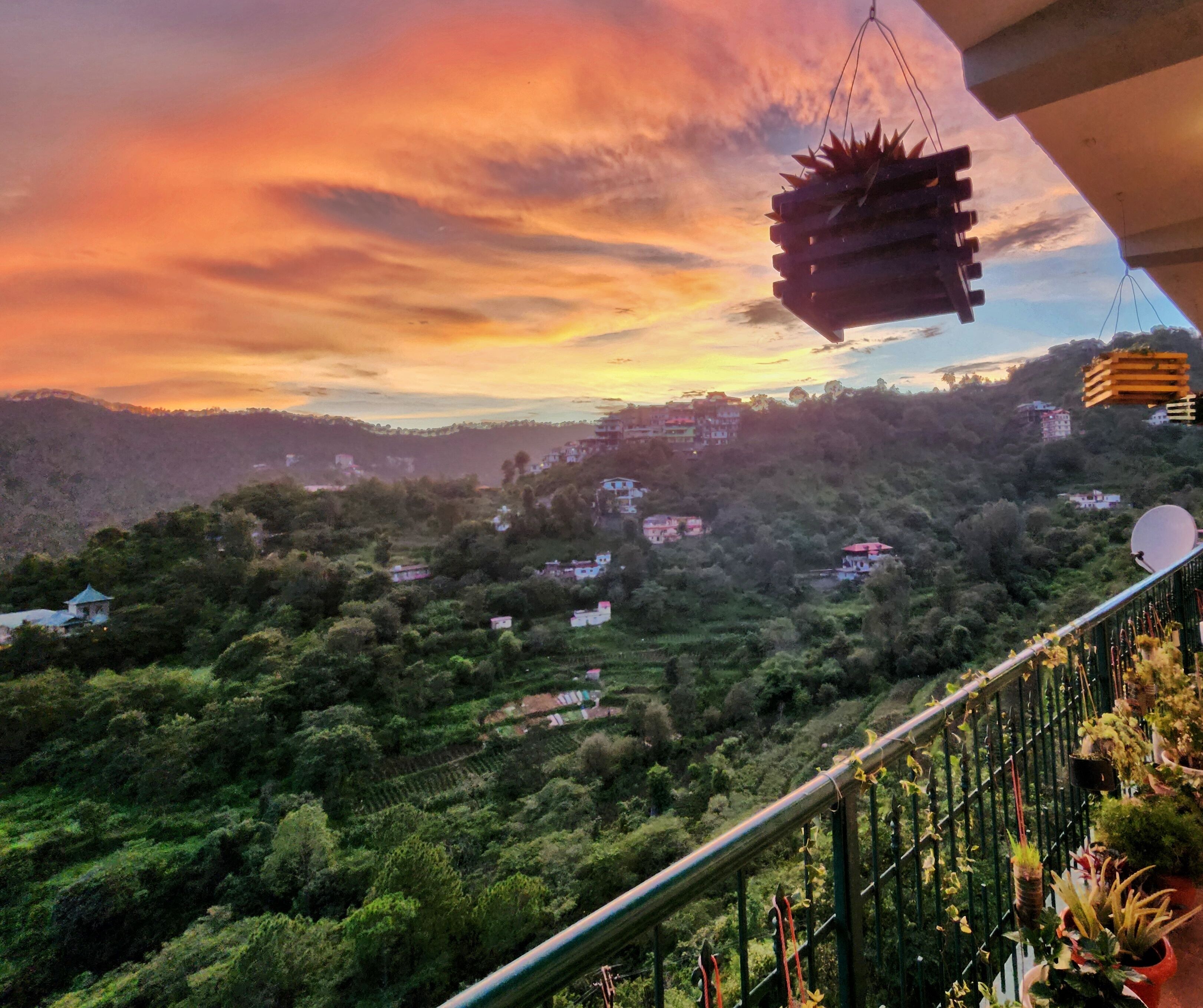 A scenic view of a hillside with scattered houses and a sunset in the background.