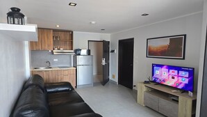 Un espacio habitable compacto con kitchenette, televisor de pantalla plana y sofá de cuero.