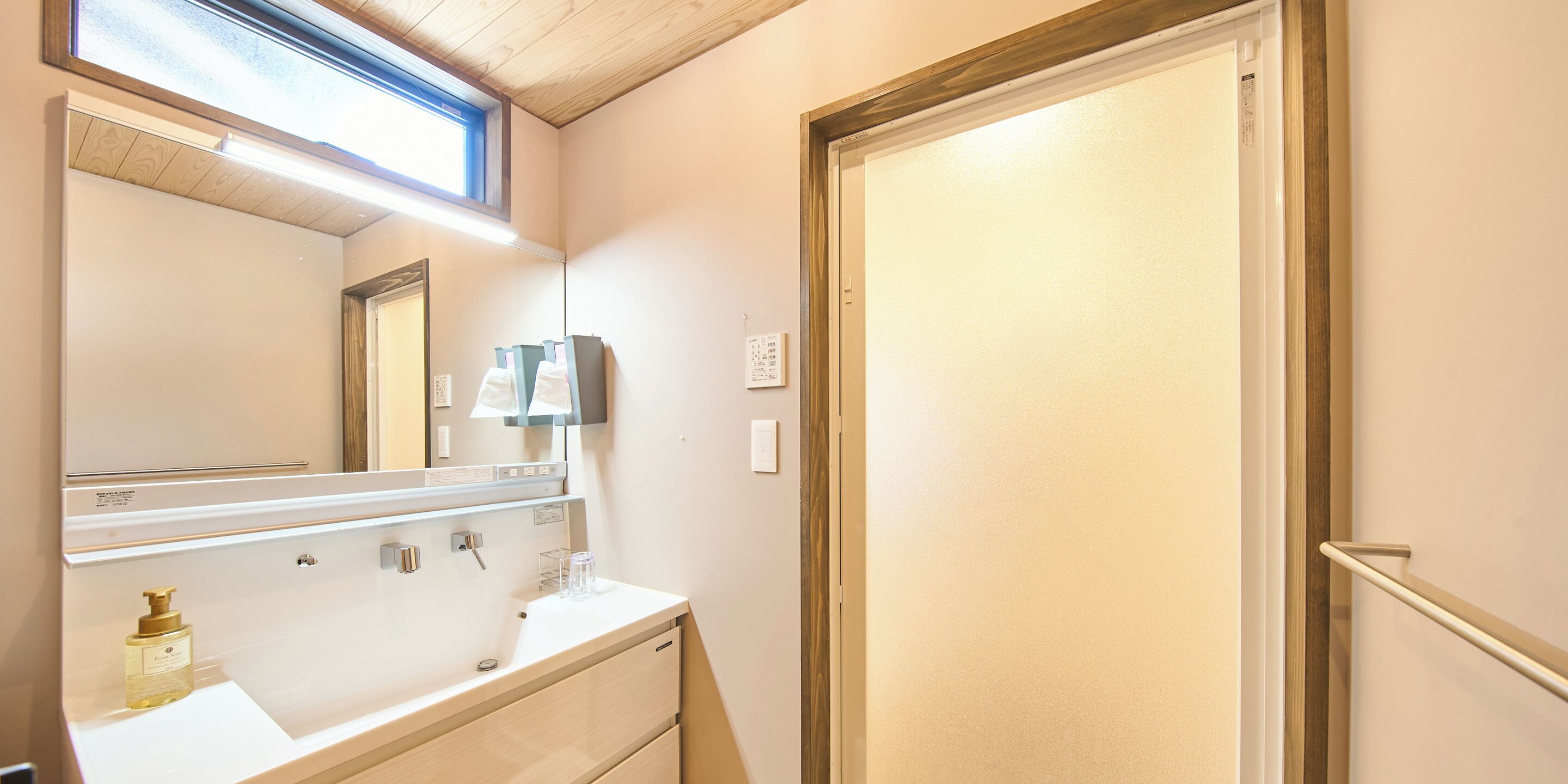 A bathroom with a mirror, two sinks, a towel rack, and a door.
