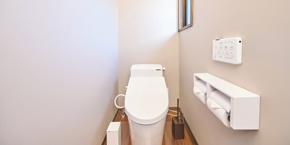 A modern bathroom with a toilet, bidet, and a wall-mounted toilet paper holder.