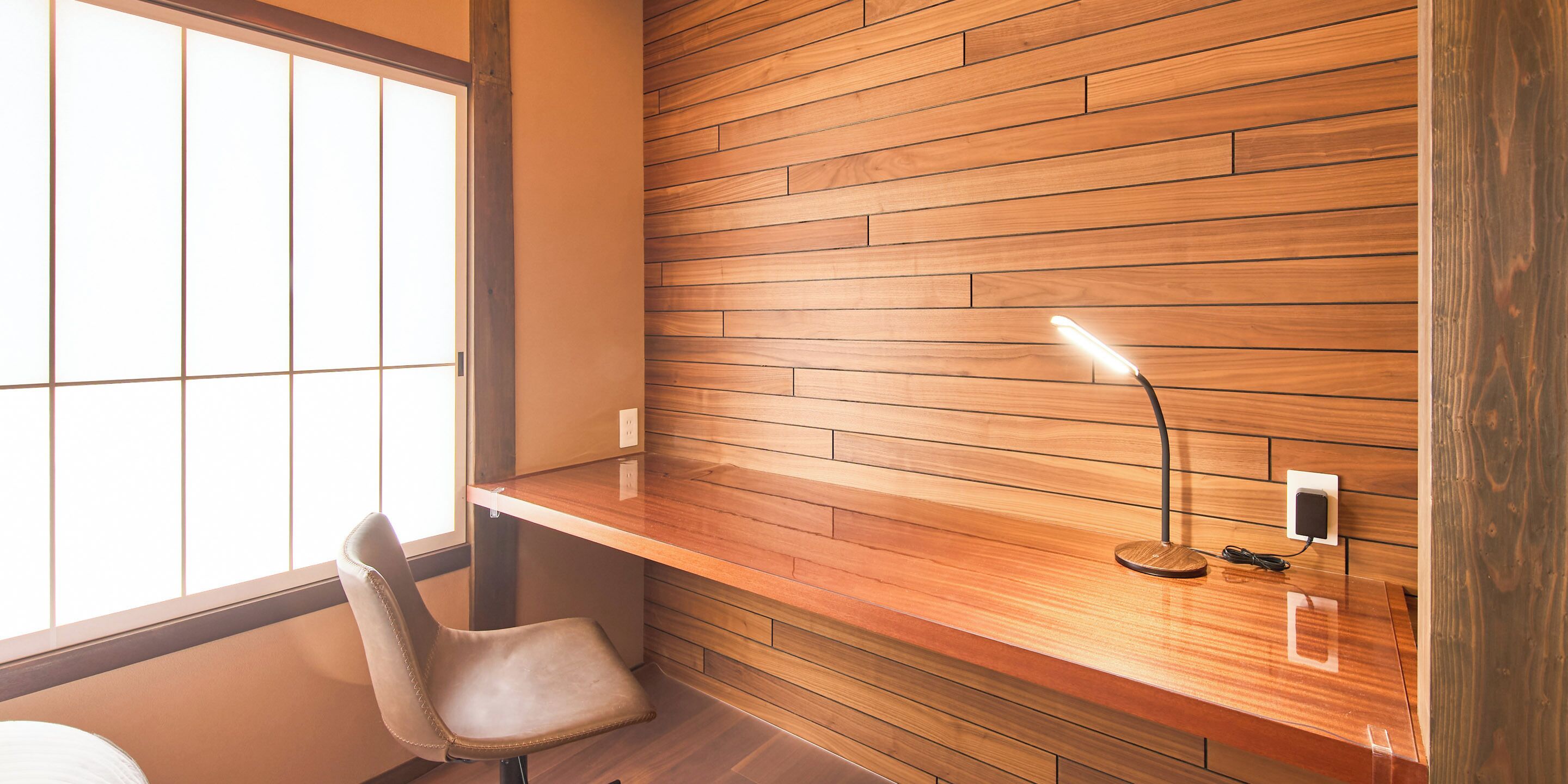 Una habitación moderna con pared de madera, un escritorio, una silla y una ventana.