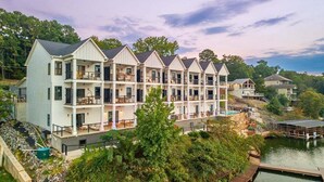 Een meerlaags hotel met balkons, een steiger en uitzicht op een meer.