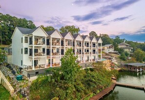 Un hotel de varios pisos con balcones, un muelle y vista al lago.