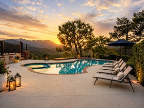 Une piscine à bord incurvé, entourée de chaises longues et offrant une vue sur les montagnes.
