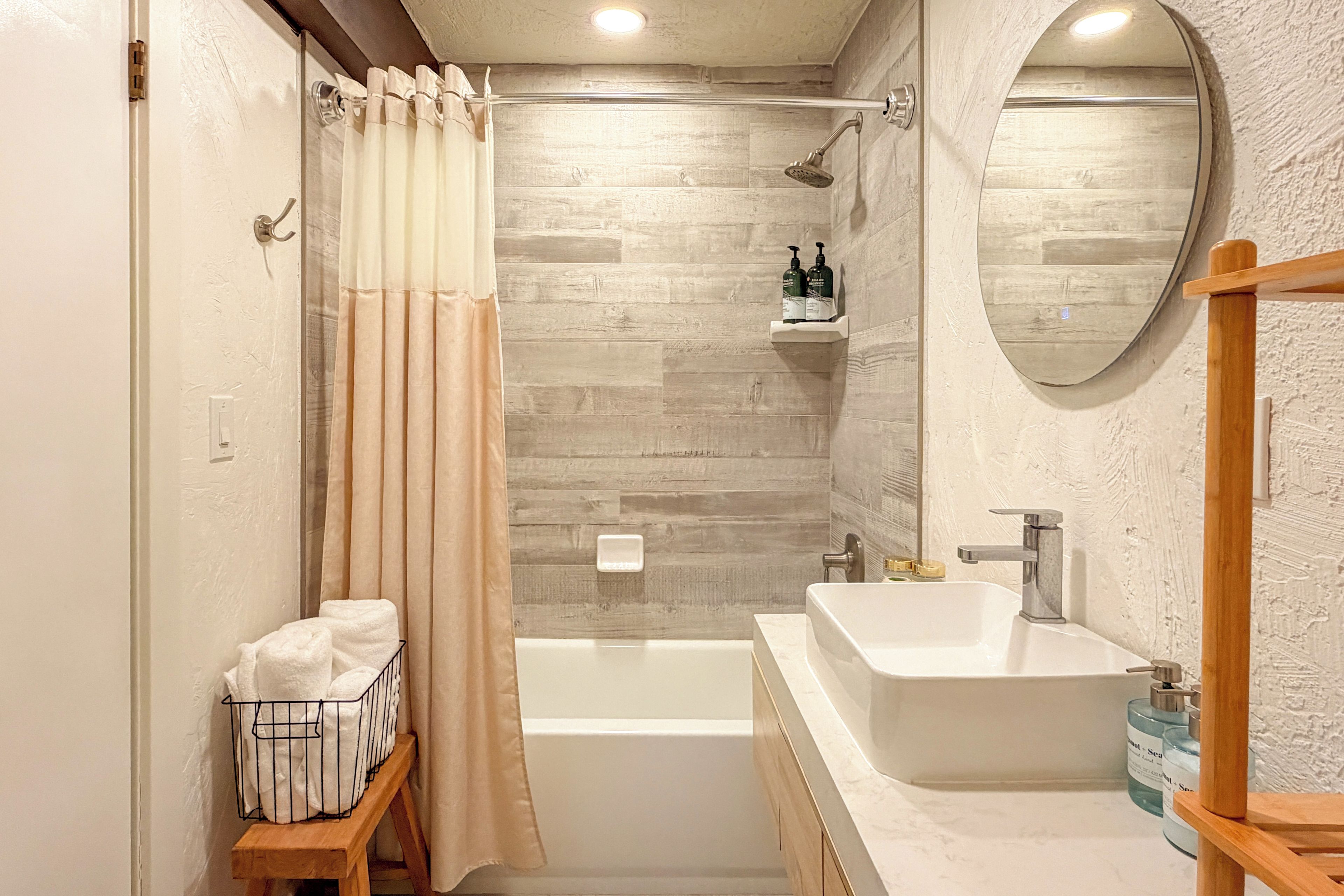 Une salle de bain moderne équipée d’une baignoire, d’une douche, d’un meuble-lavabo et d’un miroir.