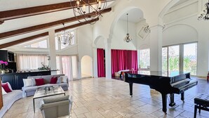 Un salón amplio con un piano de cola, un conjunto de sofás y una mesa de comedor.