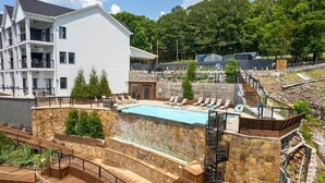A multi-story hotel with a swimming pool, outdoor deck, and a stone wall. - Side-by-Side Lake Hamilton Homes w/Dock, Pool (Hot Springs)