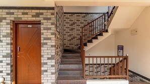A staircase with a wooden railing, a brown door with a number plate, and a tiled floor. - Treebo Arabica Valley-Coffee Plantation Retreat (Chikkamagaluru)